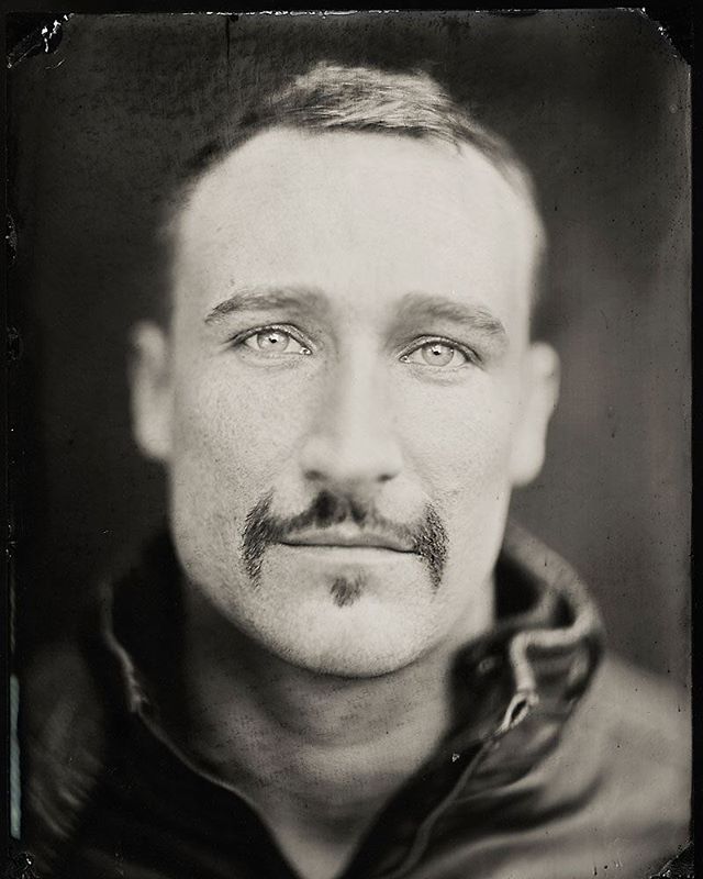 A monochrome portrait of a man with a mustache in a vintage style.