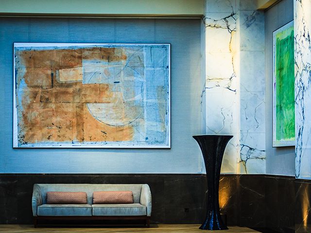 Modern interior featuring abstract art, a neutral sofa, and a sculptural vase in a serene, stylish lobby setting.