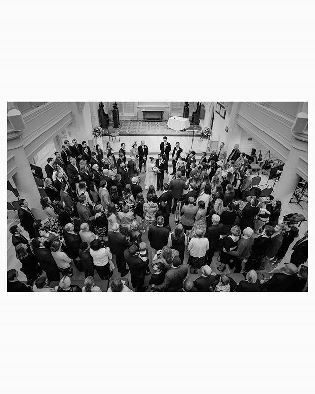 An overhead shot captures a wedding ceremony with the bride, groom, and many guests in a church, creating a timeless memory.