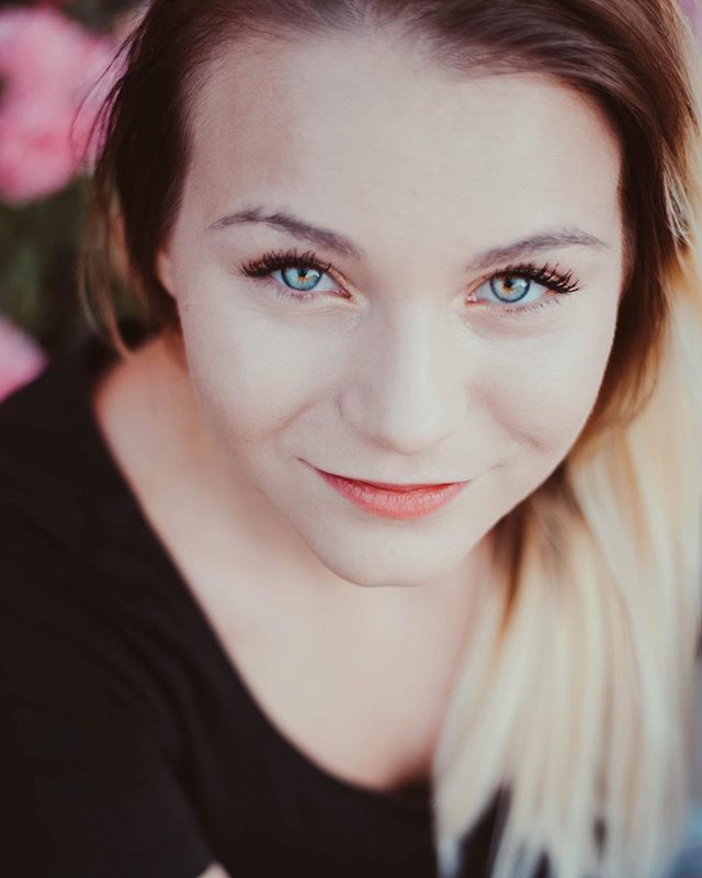 A captivating young woman with striking blue eyes looks up, her gaze filled with warmth and gentle charm.