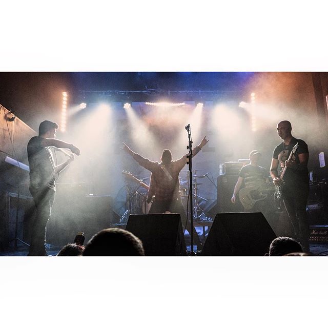 A band performs on a brightly lit stage in front of a crowd, creating an energetic and exciting atmosphere.