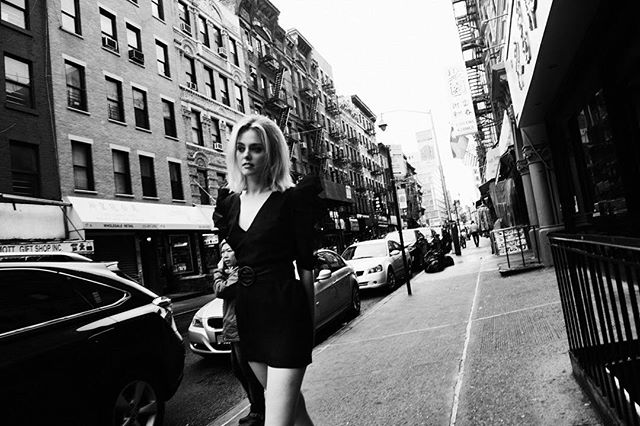 A woman walks confidently on a city street in this black and white editorial-style photo.