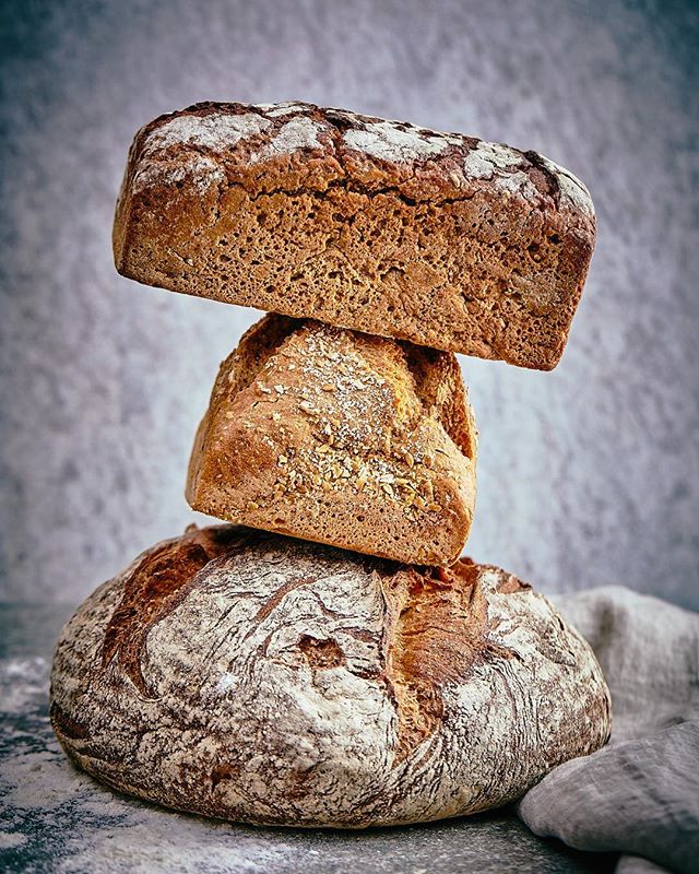 A stack of three artisan bread loaves, dusted with flour, creates an inviting still life for food marketing.