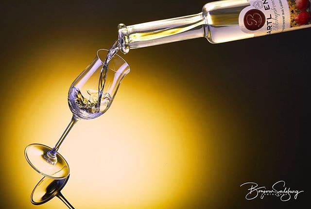 Liquor being poured into a glass from a bottle in a studio shot with warm tones.