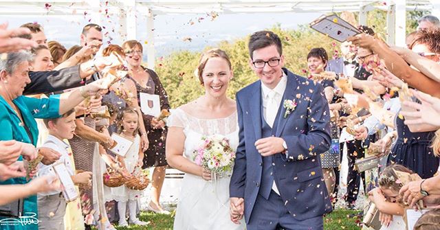 A bride and groom celebrate their wedding day as guests shower them with confetti.