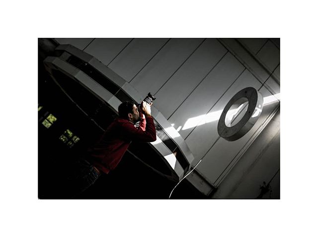 A photographer in a red shirt takes a photo in a modern building. 