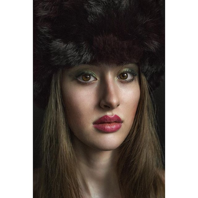 Portrait of a woman with brown eyes and fur hat in studio lighting.