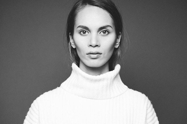 A serious woman poses in a black and white studio headshot, showcasing confidence and professionalism.