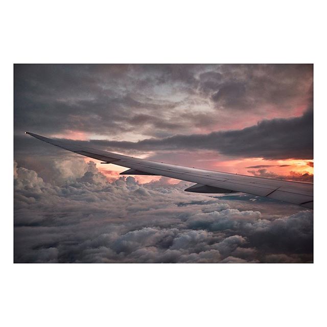 An airplane wing silhouetted against a cloudy sunset sky during flight, capturing a sense of peaceful travel and adventure.