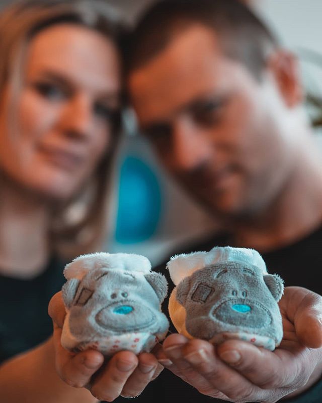 A couple holds baby booties, announcing their pregnancy with love and anticipation.