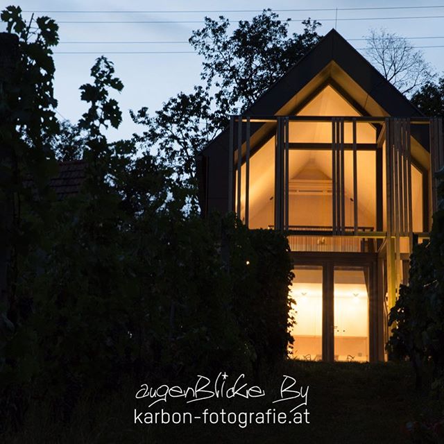 A modern house with large windows glows at twilight, showcasing architectural design and serene residential ambiance.