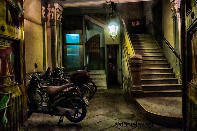 An urban courtyard at night with a staircase and motorcycles parked inside the building.