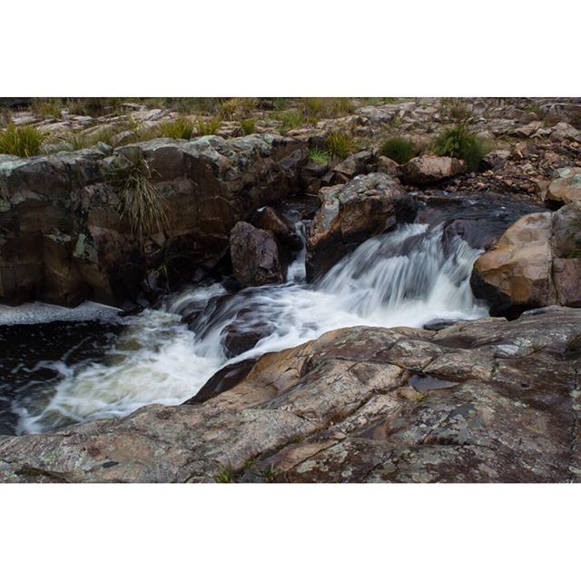 A peaceful waterfall cascades over rocks, creating a tranquil nature scene.
