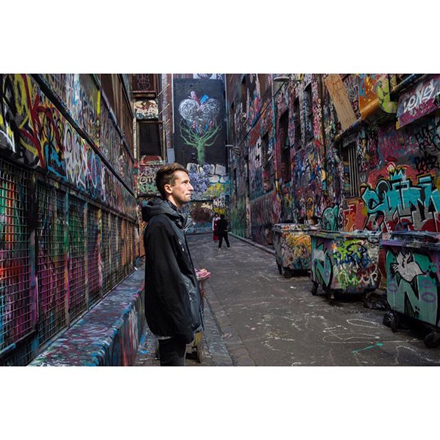 A man stands in a graffiti-filled alley, capturing the essence of urban street art and culture.