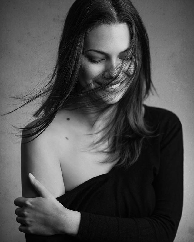 A monochrome portrait of a brunette woman with soft lighting, conveying intimacy and relaxation.