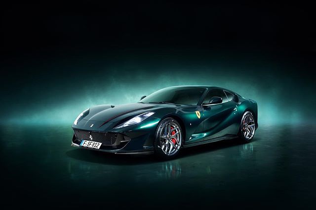 A sleek, dark green Ferrari 812 Superfast exudes luxury and power against a muted, sophisticated backdrop.
