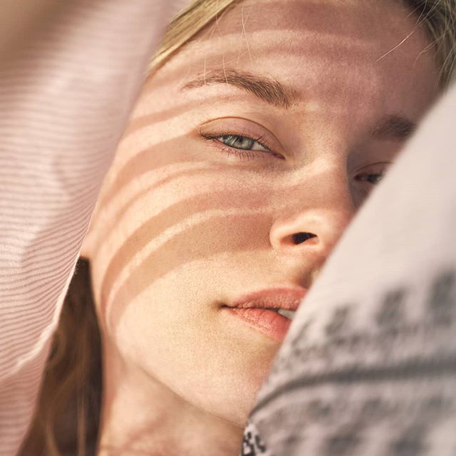 Intimate portrait of a woman's face with soft lighting and shadows creating a serene, dreamy mood.