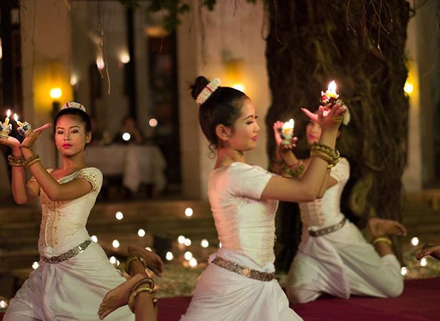 Three women perform a traditional candle dance in Cambodia, showcasing elegant and serene cultural artistry.