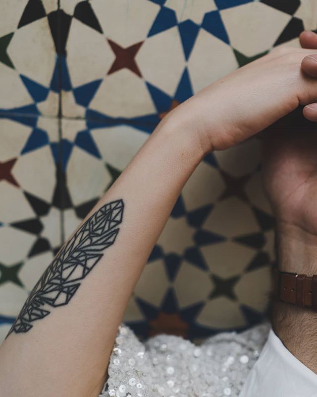A close-up shows a couple holding hands with a feather tattoo on one of their arms.