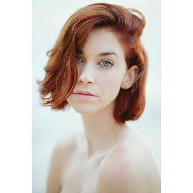 Close-up of a beautiful redhead woman with blue eyes in soft light, perfect for beauty or wellness campaigns.