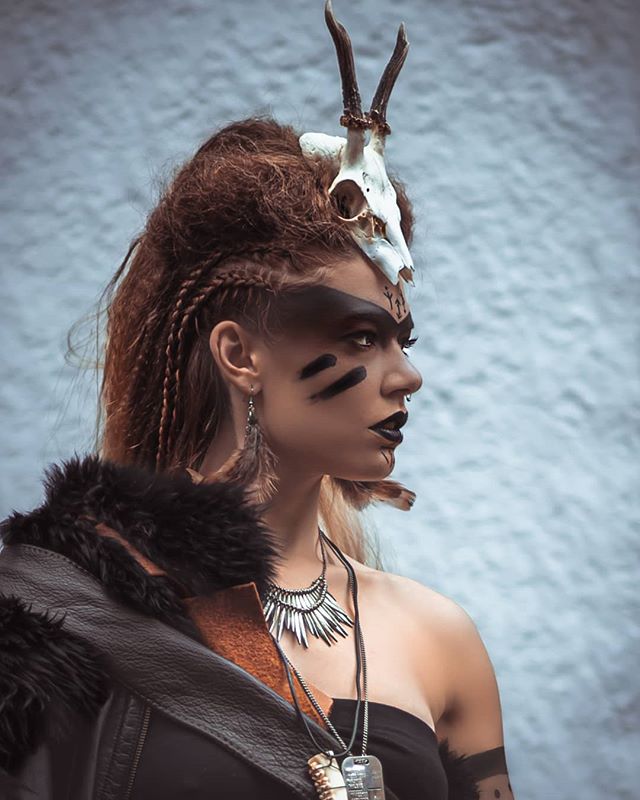 A woman with dark makeup and a skull headdress poses for a powerful and mysterious portrait.