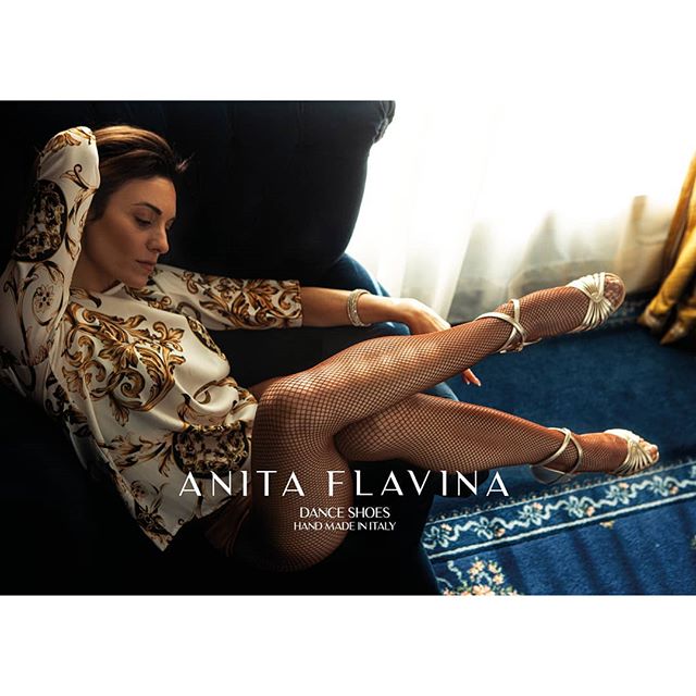 A woman lounges on a couch wearing dance shoes and fishnet stockings, showcasing an elegant fashion editorial.