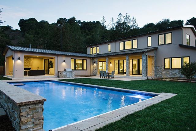 A luxurious house with a pool and green lawn in the backyard.