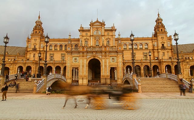 Plaza de España in Seville, Spain, with a horse-drawn carriage adding motion to the architectural scene.