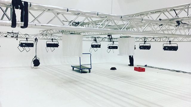 A bright studio interior with lighting rigs and a cart on a clean white floor. Modern, minimalist, great for commercial campaigns.