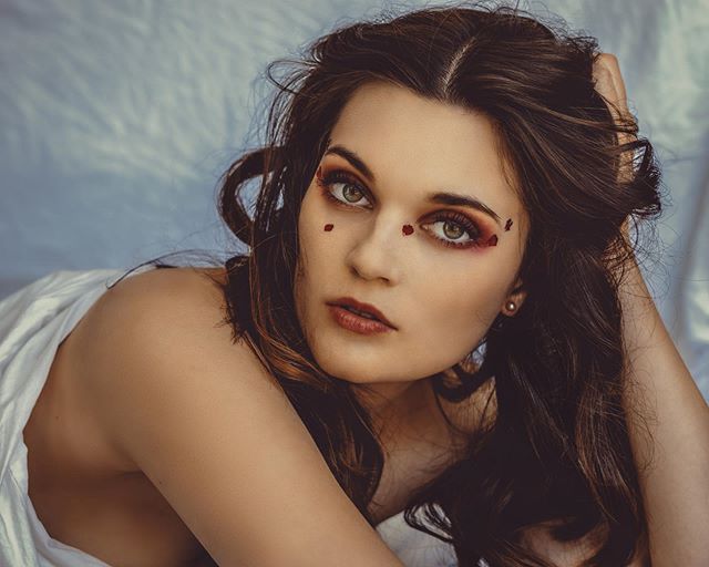 Portrait of a brunette woman with creative makeup in a dreamy, intimate setting.