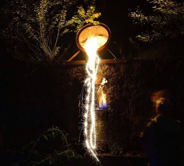 A metal pot with fire is captured in a mesmerizing long exposure at night, showcasing the beauty of metalwork and fire.