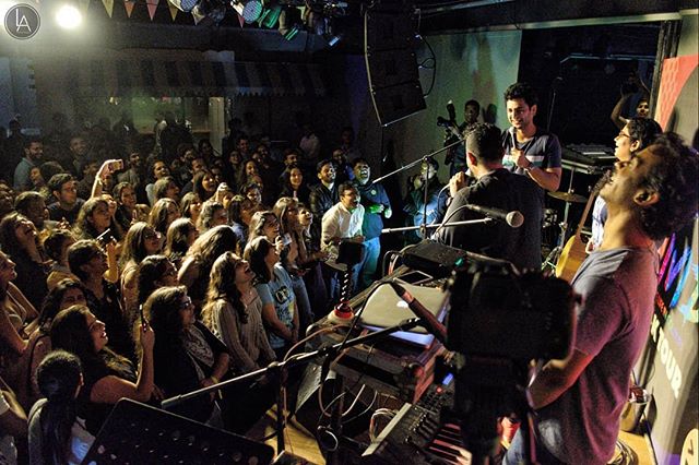 A band performs live on stage in front of an enthusiastic audience at a concert.