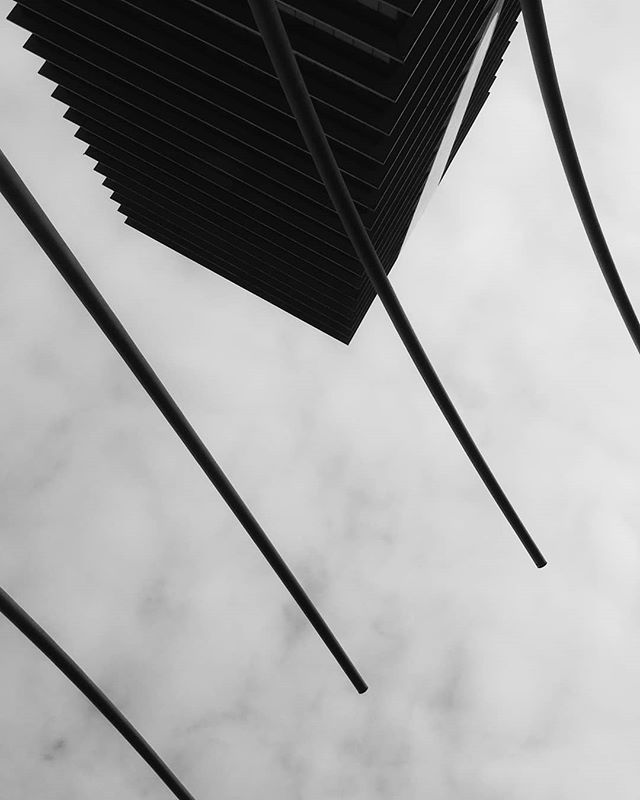 Abstract low-angle shot of a building with striking lines against a cloudy sky.