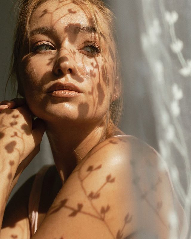 A portrait of a woman with soft, natural lighting and shadows creating an intimate, dreamy atmosphere.