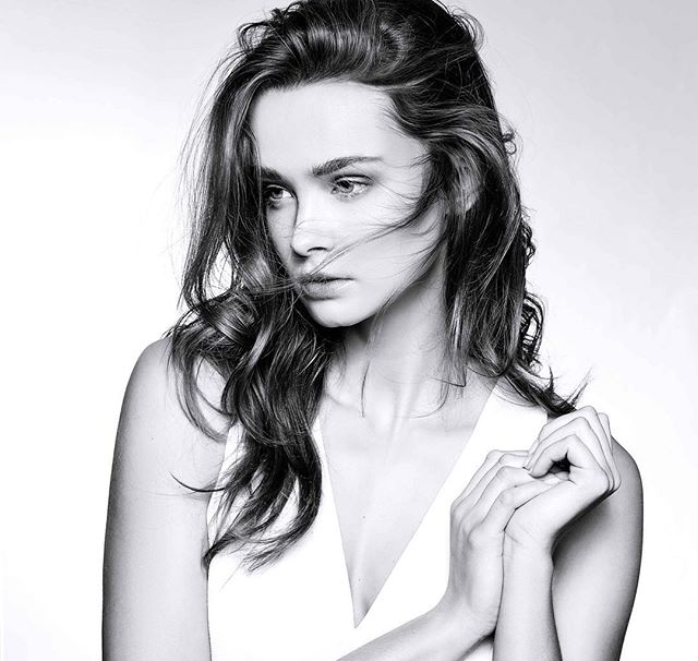 A captivating black and white portrait of a woman in soft light with a dreamy, contemplative mood, suitable for beauty or editorial use.