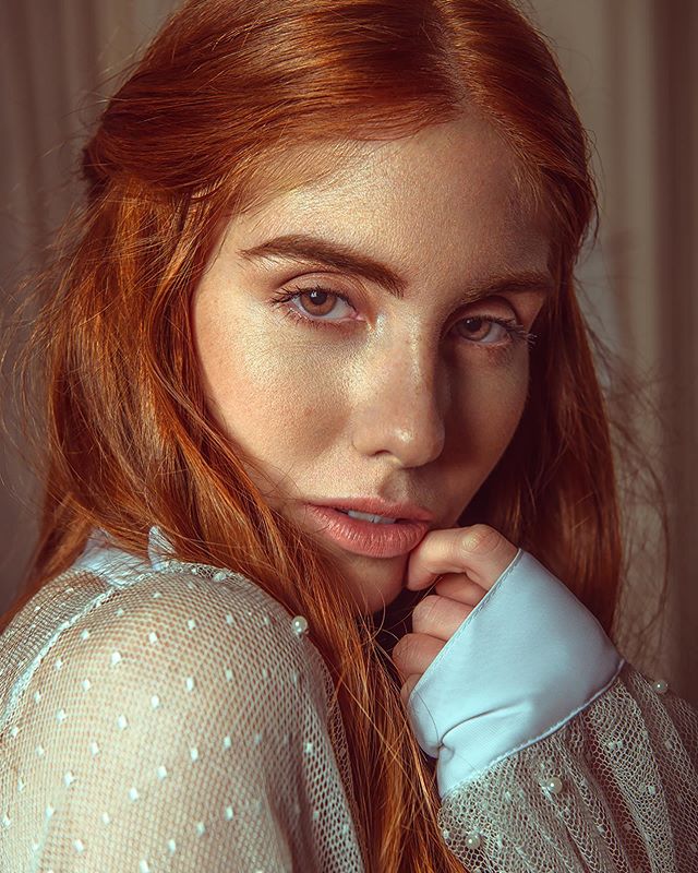 Portrait of a redhead woman with soft lighting and a dreamy expression, ideal for beauty and fashion content.